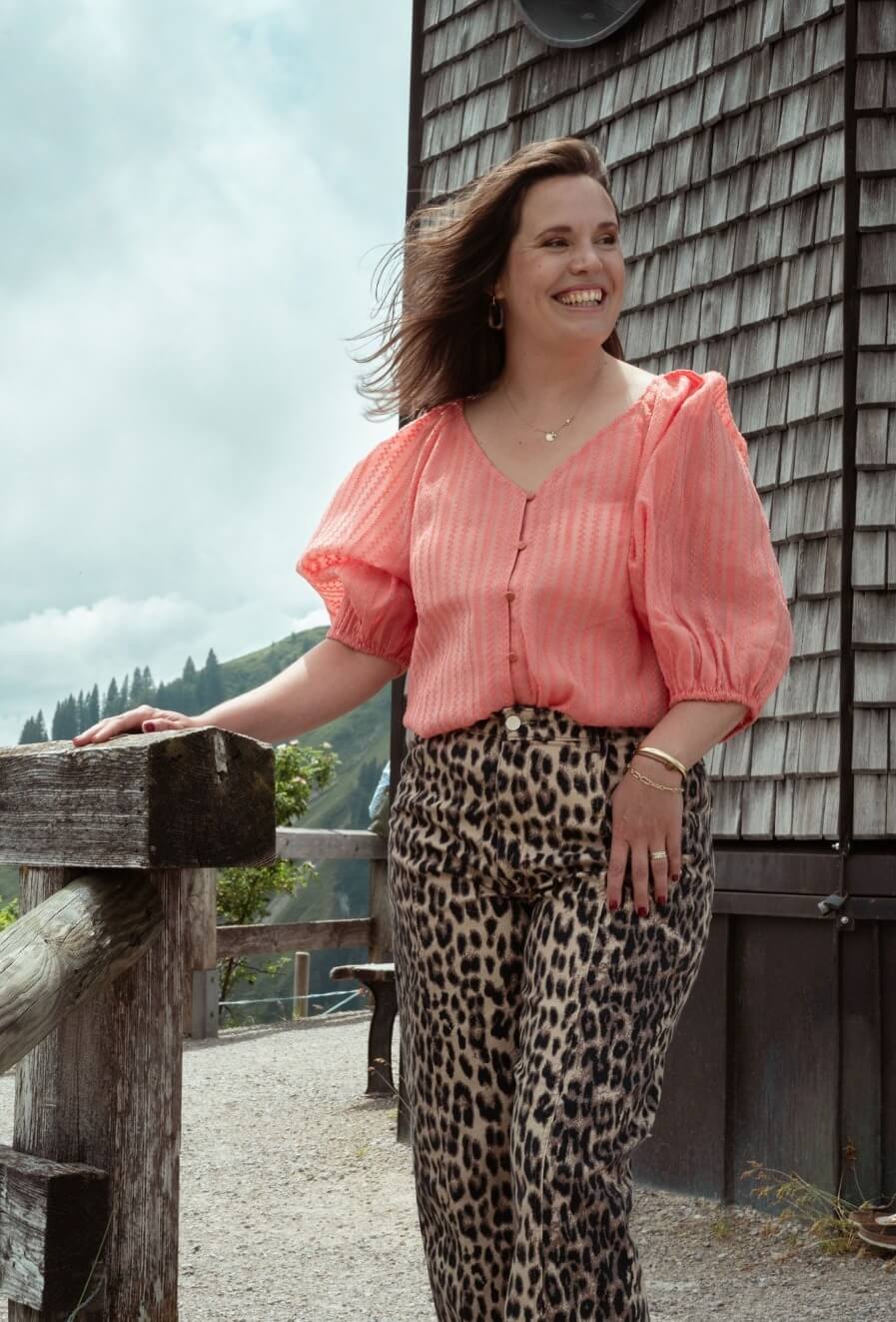 Marianne in roze blouse tegen een houten gevel